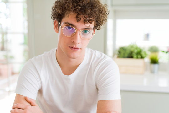 Young handsome man wearing glasses Relaxed with serious expression on face. Simple and natural with crossed arms