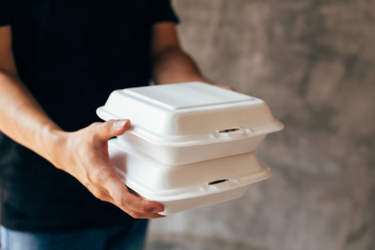 Close-up of delivery man handing a slack of foam lunch box - Foam box is toxic plastic waste. Used for recycling and environment saving concept