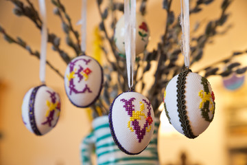 Folklike pussy willow bunch, an old tradition in Austria in the Holy Week, with artfully embroidered Easter eggs decorated with large letters, in a ceramic jug.