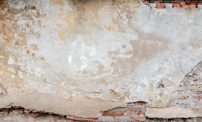 Old grungy red brick wall with peeled beige stucco background. Vintage retro plaster wall with dirty cracked scratched texture background