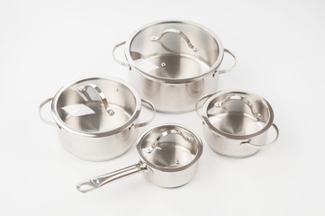 Several stainless saucepans with covers on gray background