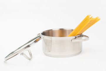 Dry spaghetti in stainless saucepan on white background