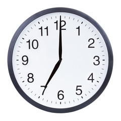 Round office clock showing seven o'clock isolated on white background