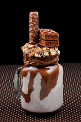 Chocolate extreme milkshake with brownie cake, chocolate paste and sweets. Crazy freakshake food trend. Copy space