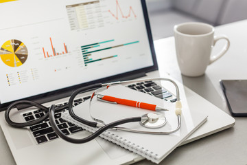 Stethoscope with clipboard and Laptop on desk,Doctor working in hospital writing a prescription. Healthcare and medical concept, test results in background, selective focus