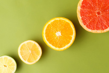Sliced grapefruit, orange, lemon and lime fruits on green background