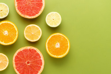 Colorful sliced fruits on green background with copy space