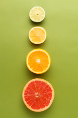Colorful fruits in row on green background. Grapefruit, orange, lemon and lime
