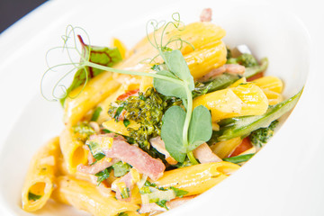 Pasta - penne with bacon and broccoli, decorated with herbs 