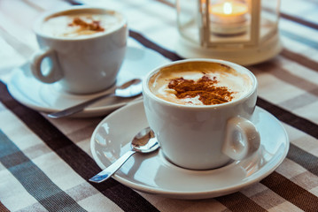 two cups of coffee on the table with klechatoy tablecloth. cappuccino.