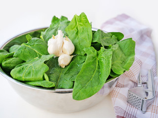 Fresh spinach leaves in metallic bowl over light background