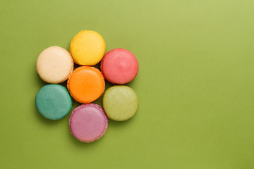 Fototapeta na wymiar Aerial view of bright colorful macaroons on green background 