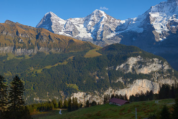 Mountain view of Monch and Eiger at sunset with old barn in Switzerland.