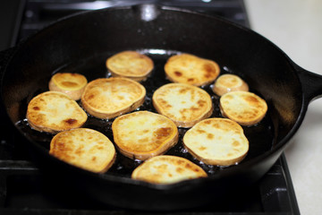 Sweet potato chips cooking in a cast iron pan.