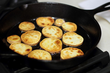 Sweet potato chips cooking in a cast iron pan.
