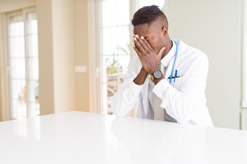 Fototapeta premium African american doctor man at the clinic with sad expression covering face with hands while crying. Depression concept.