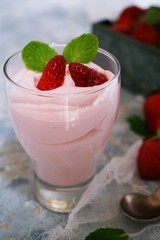 Homemade Strawberry Mousse topped with berries and mint leaf garnish, selective focus