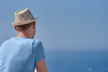 Man in sun hat relaxing against blue sea and enjoying blue sea view.