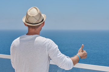 European man in sun hat is observing wonderful hotel’s view. He is enjoying his vacations.  Back view.