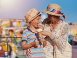 Mom and son enjoying their summer holidays and eating ice-cream in the Luna Park.
