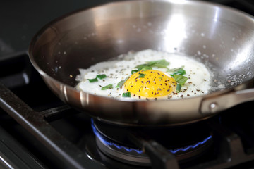 Egg sunny side up frying in a pan.