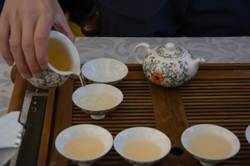 Manos sirviendo té para seis personas, costumbres de cortesía en el mundo