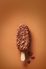 Chocolate covered ice cream with nuts on a brown background viewed from above. Top view. Copy space
