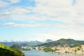 Fototapeta premium Aerial view of the beautiful city of Vitoria, Espirito Santo, Brazil and its wide bay. The city developed with its high buildings growing on the hills and into the local greenery