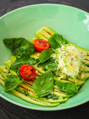 zucchini grilled with tomatoes and cream cheese, sauce and micro-greens (warm salad appetizer). food background. copy space