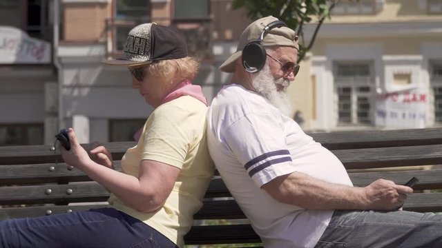 Stylish mature couple relaxing at bench in the city