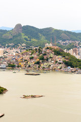 Fototapeta premium Aerial view of the beautiful city of Vitoria, Espirito Santo, Brazil and its wide bay. The city developed with its high buildings growing on the hills and into the local greenery