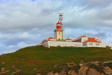 Fototapeta na wymiar Scenic landscape view of lighthouse on the hill at the Cabo da Roca (Cape Roca). It is a cape which forms the westernmost extent of mainland Portugal, continental Europe and the Eurasian land mass