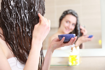 Young woman spreading oil mask