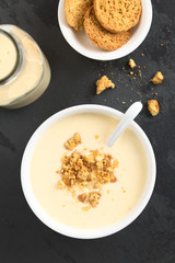 Homemade traditional Danish cold buttermilk koldskal dessert soup with pieces of crisp kammerjunker cookie on top (Selective Focus, Focus on the top of the dessert)