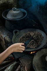 Manually roasting Ccoffee on a wood burning stove (with motion blur), Bali, Indonesia