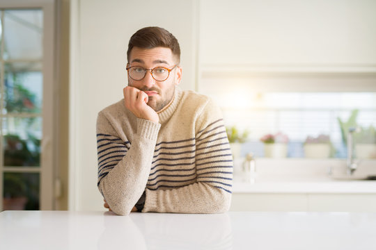 Young handsome man wearing glasses at home thinking looking tired and bored with depression problems with crossed arms.