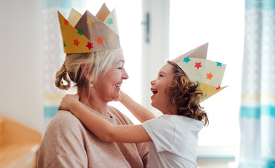A portrait of small girl with grandmother having fun at home.