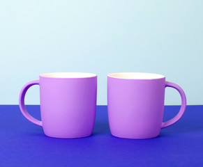 Bright new cups on a solid pastel background.