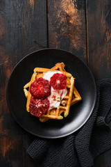 Waffles with yogurt and red Sicilian orange sauce on old dark wooden background. Top view.