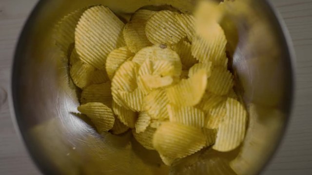 Groved potato chips falls in slow motion to the iron bowl, groved fried potatoes, snacks for beer, unhealthy fast food, 60 fps Full HD slow motion