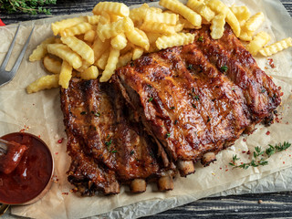 grilled pork ribs with sauce , french fries, spices, wooden background