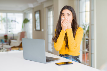 Obraz premium Young woman using computer laptop shocked covering mouth with hands for mistake. Secret concept.