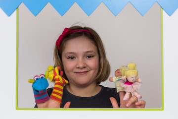 Pretty smiling little girl in small puppet theater with cloth finger puppets