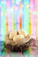 Easter eggs in the nest on wooden table and colorful abstract background