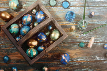 Painted colored Easter eggs in dark wooden box on dark wooden background. Boho stile.