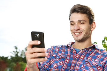 Get in touch. Selective focus on a closeup shot of a handsome guy using his smartphone outdoors