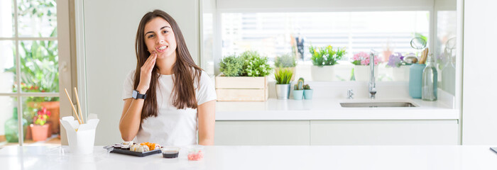 Wide angle picture of beautiful young woman eating asian sushi from delivery touching mouth with hand with painful expression because of toothache or dental illness on teeth. Dentist concept.