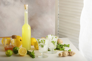 Bottle of homemade juice with ginger and lemon on light background. Horizontal