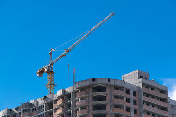 Fototapeta na wymiar construction crane is building a new home skyscraper on a background of blue sky