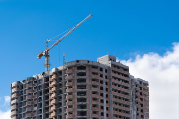 Fototapeta na wymiar construction crane is building a new home skyscraper on a background of blue sky